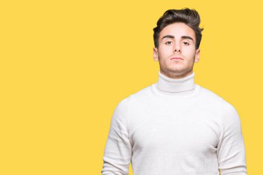 Yüzünde ciddi bir ifade ile izole arka plan üzerinde boğazlı kazak giyen genç yakışıklı adam. Basit ve doğal kameraya bakıyor.