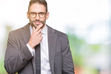 Genç yakışıklı iş adamı emin çapraz kollar ve çeneme kaldırdı el ile gülümseme ile kameraya bakarak izole arka plan üzerinde. Pozitif düşünce.