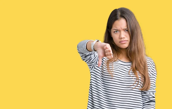 若い美しいブルネット女性の不幸と怒りの拒否反応を示さずとジェスチャーを親指で否定的な分離の背景にストライプのセーターを着ています 不適切な表現 — ストック写真