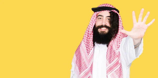 阿拉伯商人长头发 戴着传统的 Keffieh 一边用手指指着五 一边微笑着自信和快乐 — 图库照片
