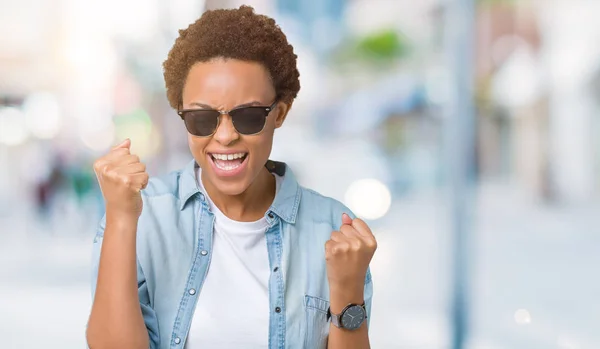 美丽的年轻非洲裔美国妇女戴着太阳镜在孤立的背景非常高兴和兴奋做赢家的手势与手臂抬起 微笑着 尖叫着要成功 庆祝理念 — 图库照片