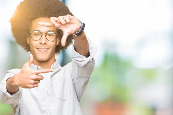アフロ髪眼鏡を手で作るフレームと幸せそうな顔で指を笑顔の若いアフリカ系アメリカ人 創造性と写真のコンセプト — ストック写真