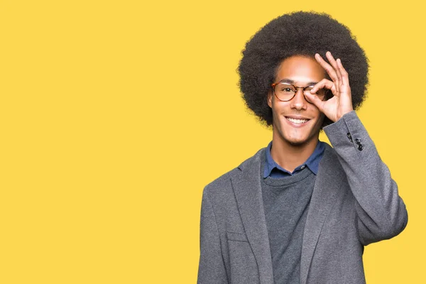 非洲青年美国商人戴着非洲头发戴眼镜做确定的手势与手微笑 眼睛通过手指看着快乐的脸 — 图库照片