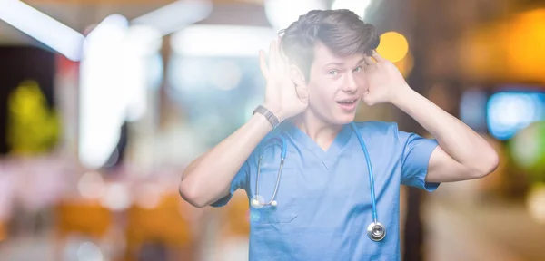 Νεαρός Γιατρός Φορώντας Ιατρική Στολή Πάνω Από Απομονωμένα Φόντο Προσπαθεί — Φωτογραφία Αρχείου