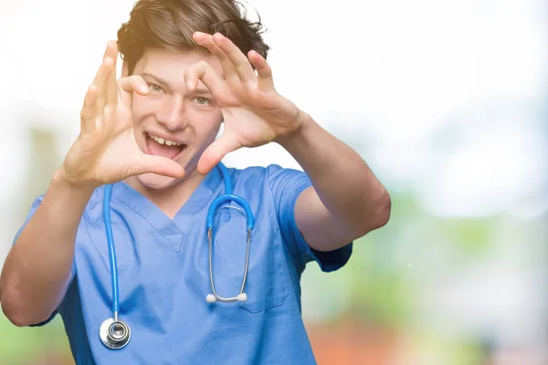 ハートマークと手で形を示す愛の笑みを浮かべて隔離された背景に医療制服を着て若い医者 ロマンチックな概念 — ストック写真