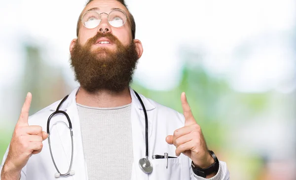 Ung Blond Läkare Man Med Skägg Bär Medicinsk Coat Förvånad — Stockfoto
