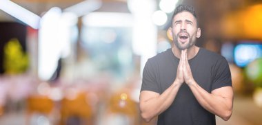 Yakışıklı delikanlı yalvarıyor ve umut ifade yüzünde çok duygusal ve endişe ile birlikte elleriyle dua izole arka plan üzerinde. Bağışlanmak. Din kavramı.