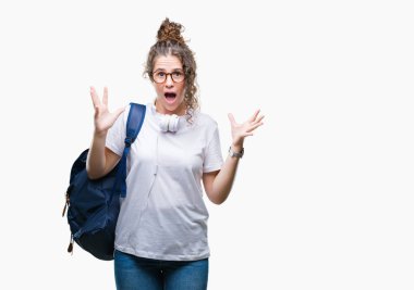 Sırt çantası ve kulaklık üzerinde giyen genç esmer öğrenci kız arka plan deli kutluyor izole ve crazy arms ile başarı için kaldırdı ve heyecanlı çığlık gözler kapalı. Kazanan kavramı