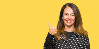 Seyir ve başparmak yanında yukarıyı mutlu yüz ile gülümseyen moda ceket giyen güzel orta yaş kadın.