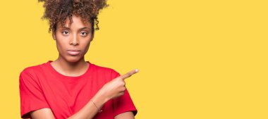 Güzel genç Afro-Amerikan kadın yüzünden izole reklam, ciddi ve sakin yüz gösterilen yan el parmak ile işaret arka plan