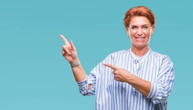 Atrractive üst düzey beyaz Kızıl saçlı kadın gülümseyerek ve iki elleri ve parmakları ile tarafına işaret kamera bakarak izole arka plan.