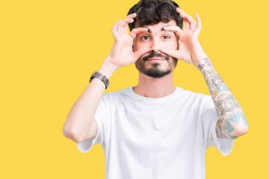 Parmaklarıyla, Uykulu ve sabah yorgunluk için yorgun gözlerini açmaya çalışırken izole arka plan üzerinde beyaz t-shirt giyen genç yakışıklı adam