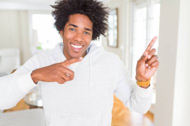 Afro-Amerikan adam sweatshirt giyen gülümseyerek ve yan iki el ve parmak ile işaret kamera bakıyor.