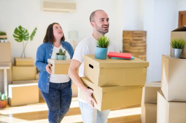 Genç çift yeni bir eve hareket, mutlu tutan karton kutular gülümseyen