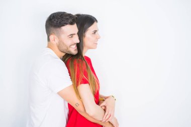 Yan bakarak beyaz izole arka plan üzerinde birlikte genç güzel çift, kendine güvenen bir gülümseme ile doğal yüz ile profil poz dinlenmek.