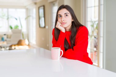 Güzel genç kadın bir fincan siyah kahve içerken çenesi üzerinde eliyle soru, dalgın ifade yi düşünüyor. Düşünceli bir yüzle gülümsüyor. Şüphe kavramı.