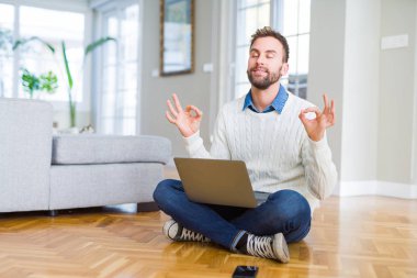 Yakışıklı adam bilgisayar dizüstü bilgisayar kullanarak çalışma giyen rahatlayın ve gözleri parmakları ile meditasyon jest yapıyor kapalı gülümseyerek. Yoga konsepti.