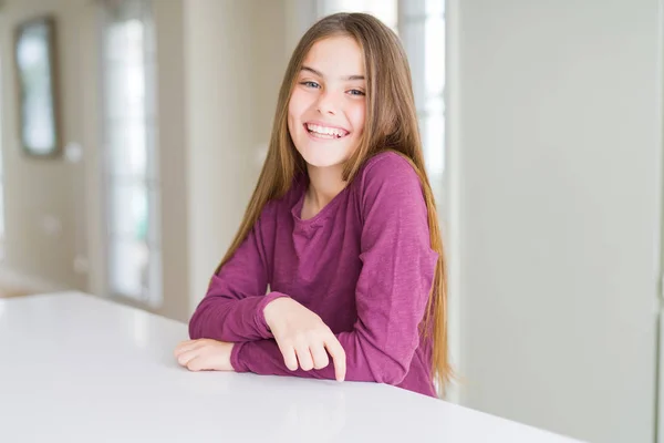 顔に幸せでクールな笑顔と白いテーブルの上に美しい若い女の子の子供 ラッキーな人 — ストック写真