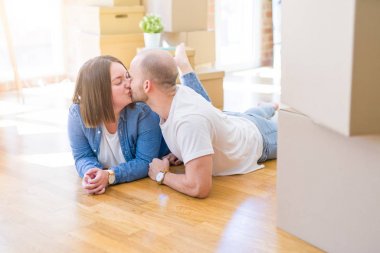 Yeni bir evin katında yatan aşık genç çift, yeni bir daireye taşınmak için çok mutlu gülümseyen, karton kutular civarı