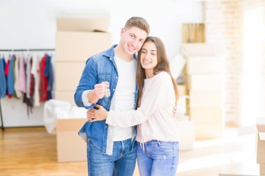 Güzel genç çift aşık ve yeni ev, yeni bir daireye hareket mutlu gülümseyen anahtarları gösteren sarılma