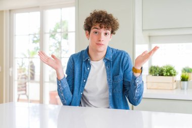 Genç yakışıklı adam evde rahat kot ceket giyen silah ve elleri ile habersiz ve karışık ifade kaldırdı. Şüphe kavramı.