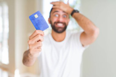 Kredi kartı başına, el ile vurguladı tutan yakışıklı İspanyol adam şok utanç ve sürpriz suratla, öfkeli ve sinirli. Korku ve hata için üzgün.