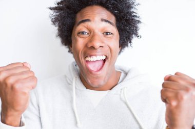 Beyaz arka plan üzerinde afro saçlı yakışıklı afro-amerikan adam gülümseyerek zafer kutlayan kaldırdı kolları ile başarı için heyecanlı. Kazanan kavramı.