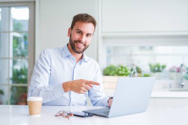 Yakışıklı adam bilgisayar laptop kullanarak çalışan ve çok mutlu el ve parmak ile işaret kahve bir fincan içme