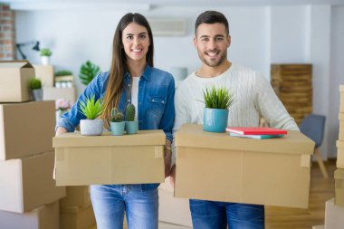 Genç çift yeni bir ev, yeni bir dairede mutlu tutan karton kutular gülümseyen hareket