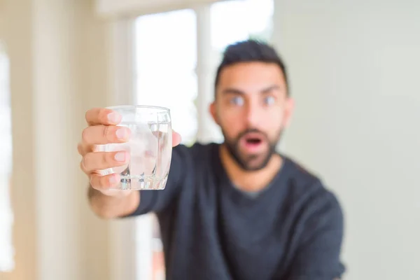 驚きの顔でショックで恐怖の水の新鮮なガラスを飲むハンサムなヒスパニックの男は 恐怖の表情で恐怖と興奮 — ストック写真