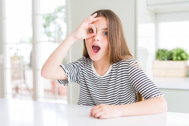 Çizgili tişört giyen güzel genç kız çocuk ok jest yaparak şaşırmış yüzüyle şoke oldu, göz parmaklarından bakıyor. İnanmayan ifade.