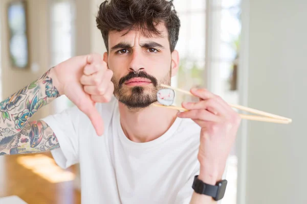 Młody Człowiek Jedzenia Asian Sushi Pomocą Pałeczek Gniewną Twarzą Negatywny — Zdjęcie stockowe