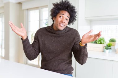 Afrikalı Amerikan adam kış kazak clueless ve kollar ve elleri ile karıştı ifade giyiyor kaldırdı. Şüphe kavramı.