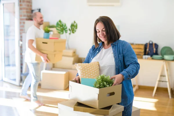 Young couple moving to new apartment, beautiful woman moving cardboard boxes and smiling happy