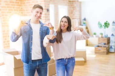 Güzel genç çift yüzünde gülümseme ile emin görünümlü yeni bir eve hareket, parmakları gururlu ve mutlu kendini işaret.