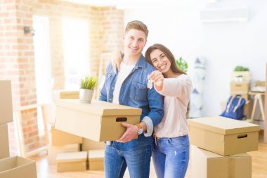 Güzel genç çift aşık ve yeni ev, yeni bir daireye hareket mutlu gülümseyen anahtarları gösteren sarılma