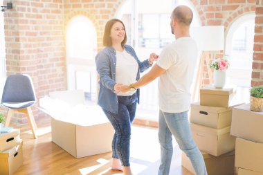 Yeni evde karton kutular etrafında dans genç çift, çok mutlu yeni ev gülümseyen kutluyor