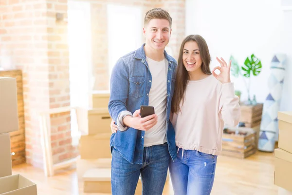 Bela Jovem Casal Mudando Para Uma Nova Casa Usando Smartphone — Fotografia de Stock