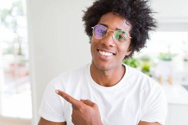 Afrika kökenli Amerikalı adam neşeli bir gülümseme ile el ve parmak kadar yan yüzünde mutlu ve doğal ifade ile işaret yüz ile gözlüklü