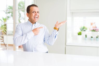 El ile sunulması ve parmak ile işaret ederken evde şaşırdım ve kameraya gülümseyen oturan orta yaş adam.