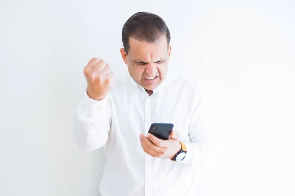 中年男子使用智能手机在白墙上恼火和沮丧的喊叫与愤怒 疯狂和大喊大叫与举手 愤怒的概念 — 图库照片