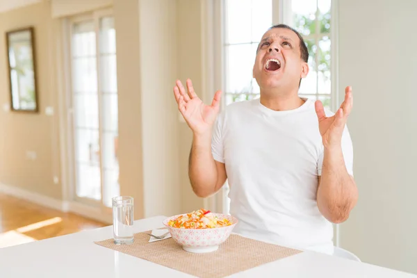 家でご飯を食べている中年の男は 腕を上げて目を閉じて興奮して成功を祝う 勝者のコンセプト — ストック写真