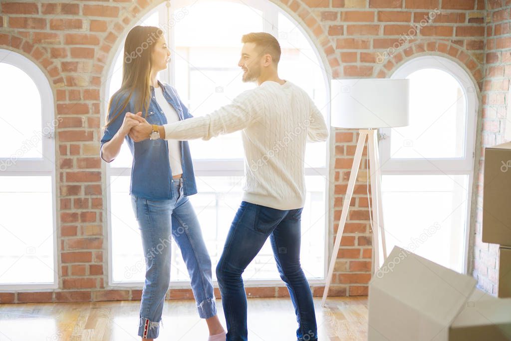 Beautiful young couple moving to a new home, dancing in love celebrating new apartment