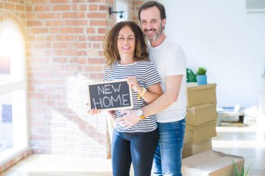 Orta yaş Senior çift yeni bir eve hareket, yeni bir ev metin ile bir tahta tutan Apartmant aşık mutlu gülümseyen