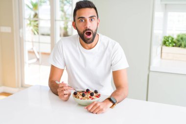 Sabah ları evde sağlıklı kahvaltı yiyen yakışıklı İspanyol adam sürpriz bir yüzle şokta korkmuş, korkuyla korkmuş ve heyecanlı ifade