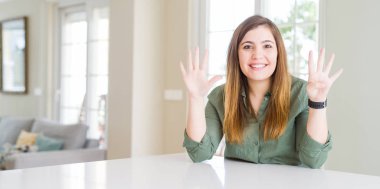 Evde gösteren ve parmakları ile işaret eden güzel genç kadın emin ve mutlu gülümserken dokuz numara.