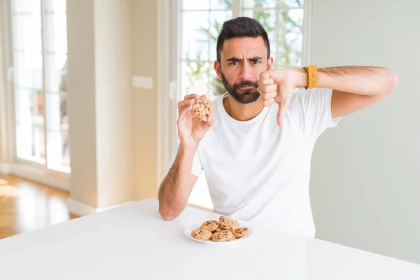 Όμορφος Ισπανικός Άνθρωπος Που Τρώει Μπισκότα Τσιπ Σοκολάτας Θυμωμένο Πρόσωπο — Φωτογραφία Αρχείου