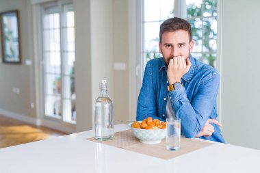 Yakışıklı adam evde köfte ve domates sosu ile makarna yeme stresli ve ağız tırnak ısırma elleri ile sinirli görünümlü. Anksiyete sorunu.