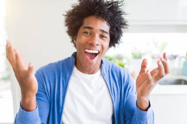Afrika kökenli Amerikalı adam evde çılgın ve başarı için hayran kaldırdı Kollarını açarak kutluyor ve heyecanlı çığlık gözleri açık. Kazanan kavramı