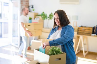 Genç çift yeni daireye hareket, güzel kadın karton kutular hareket ve mutlu gülümseyen